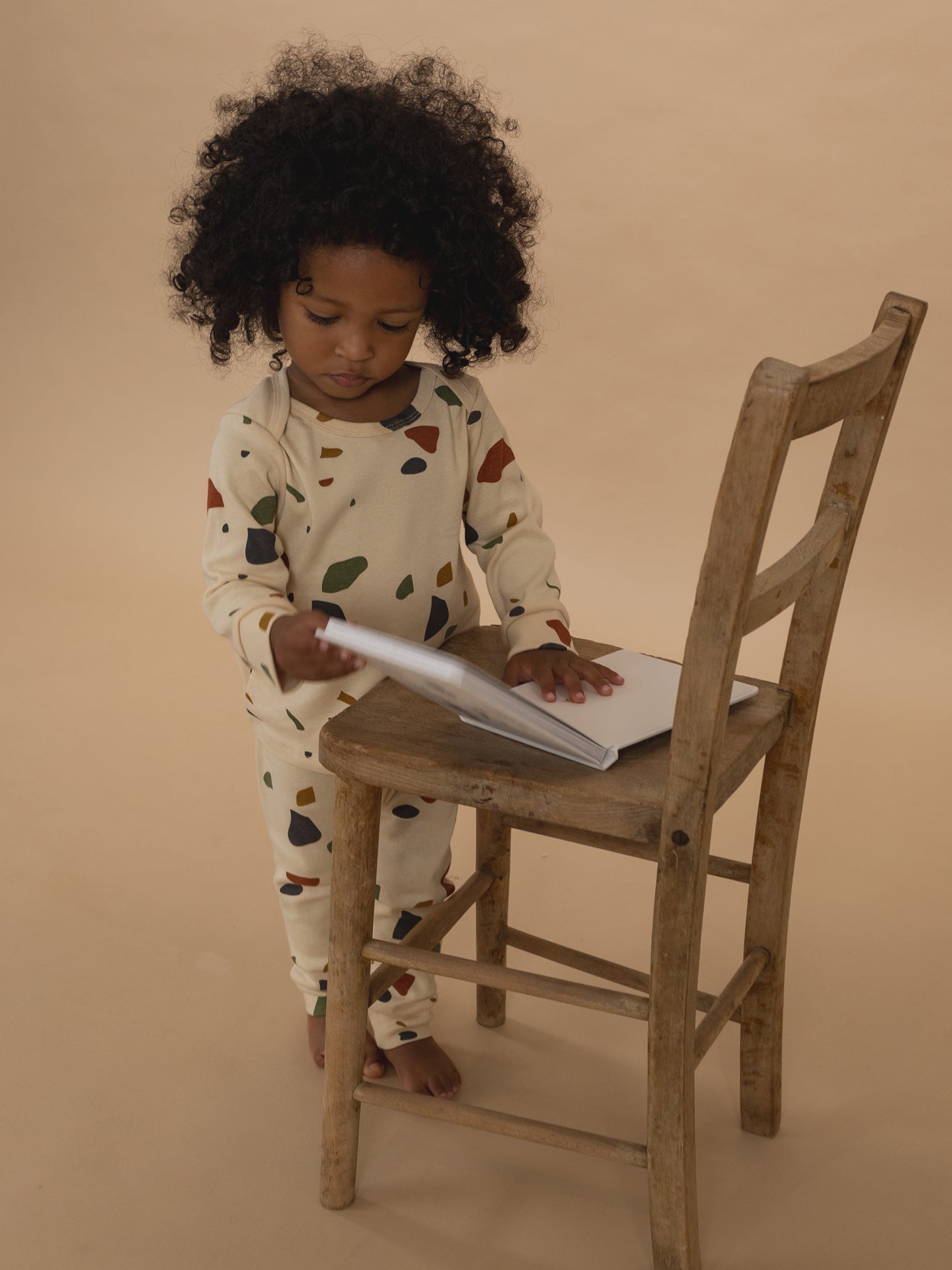 toddler in cream ribbed cotton long-sleeved top & leggings set with terrazzo print, reading book