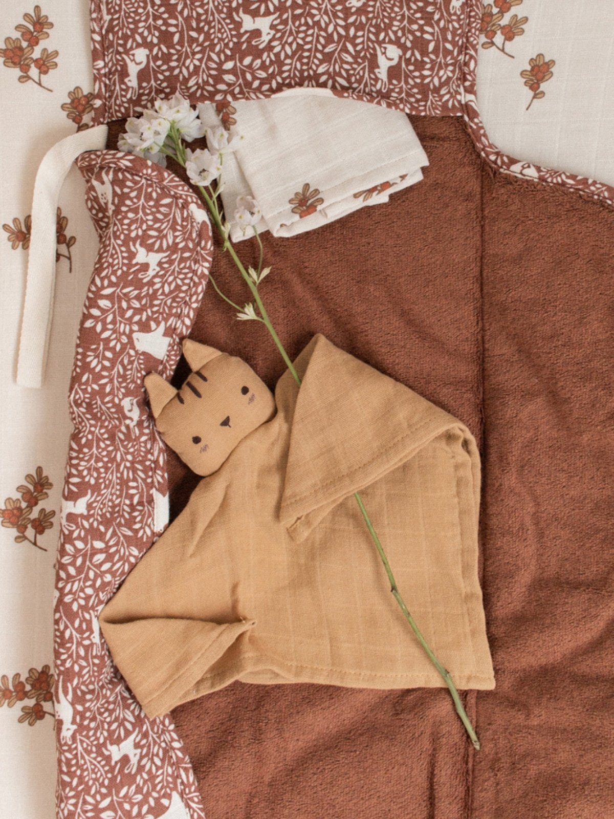 Folded brown fabric with a small plush toy on a patterned fabric background