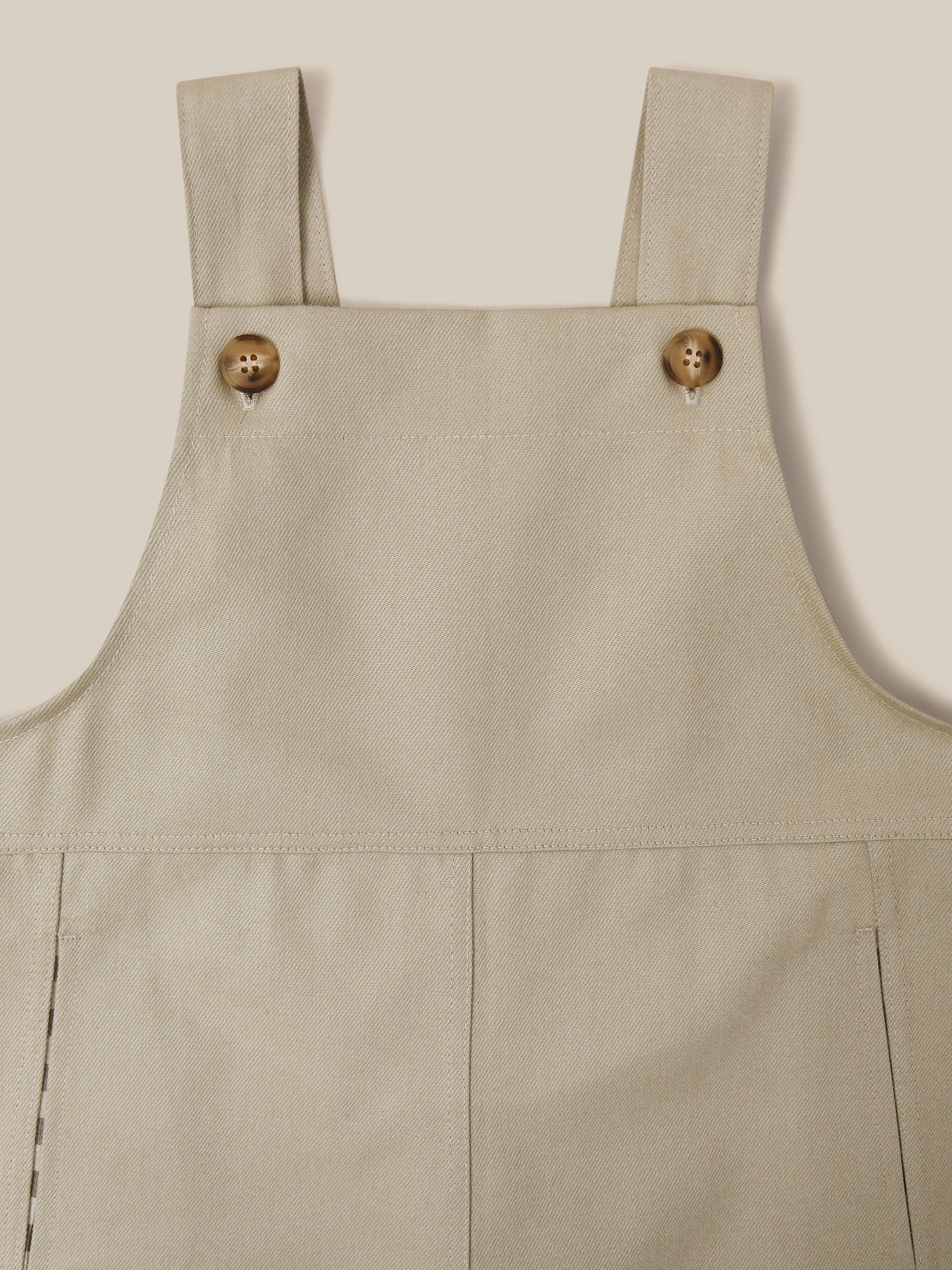close up of twill cotton oversized farmers dungarees in grey with buttons & side in-seam pockets with gingham finish