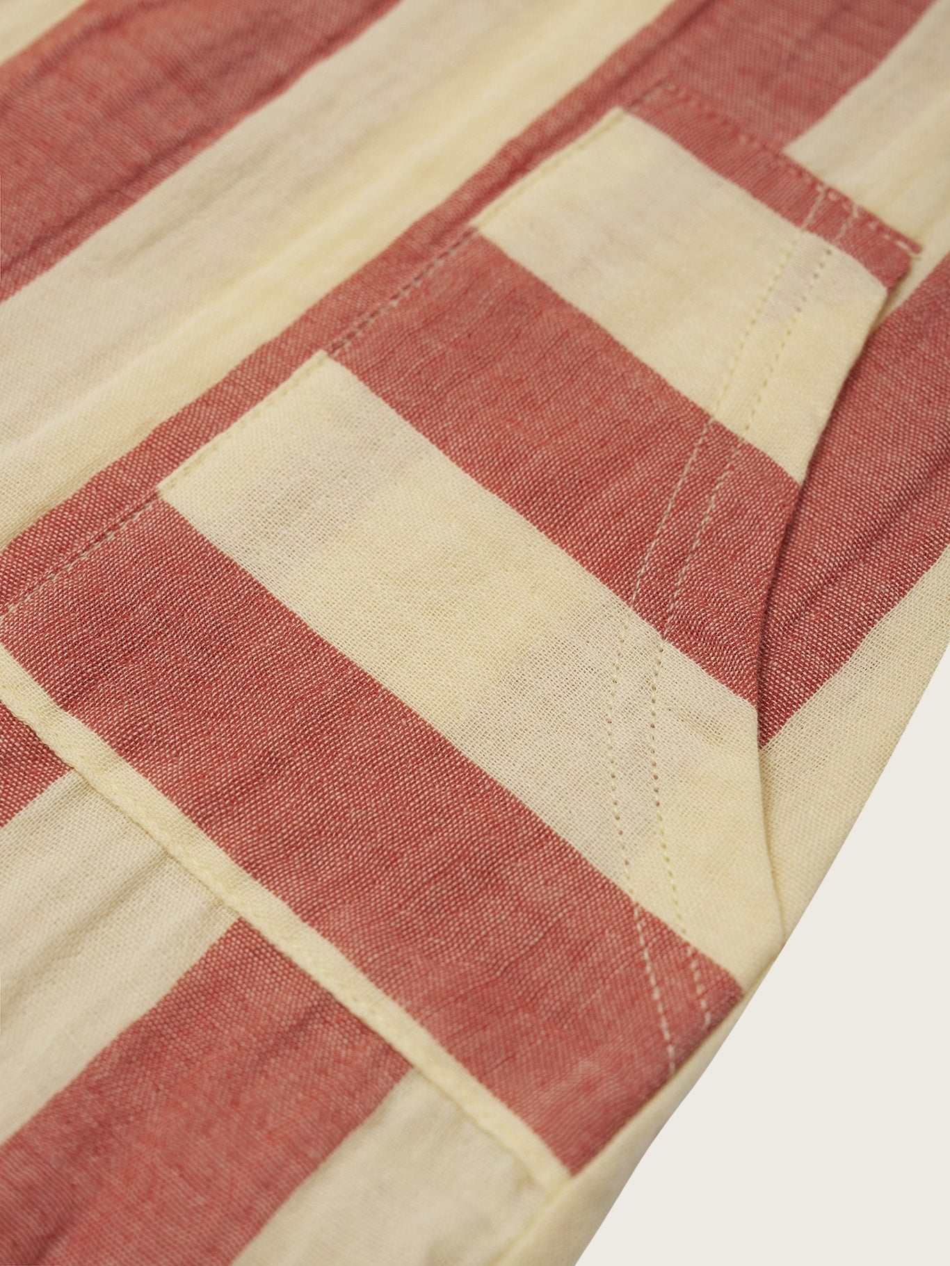 Close-up of a fabric with red and beige geometric pattern on a white background