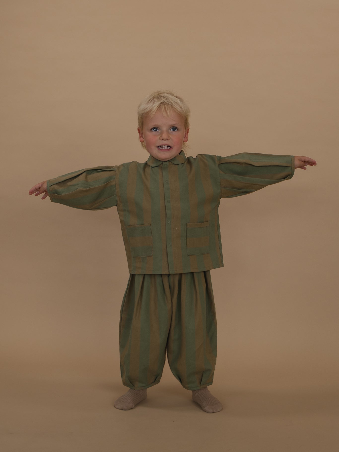 toddler in stripes lodge shirt with balloon sleeves with matching balloon pants standing with arms out
