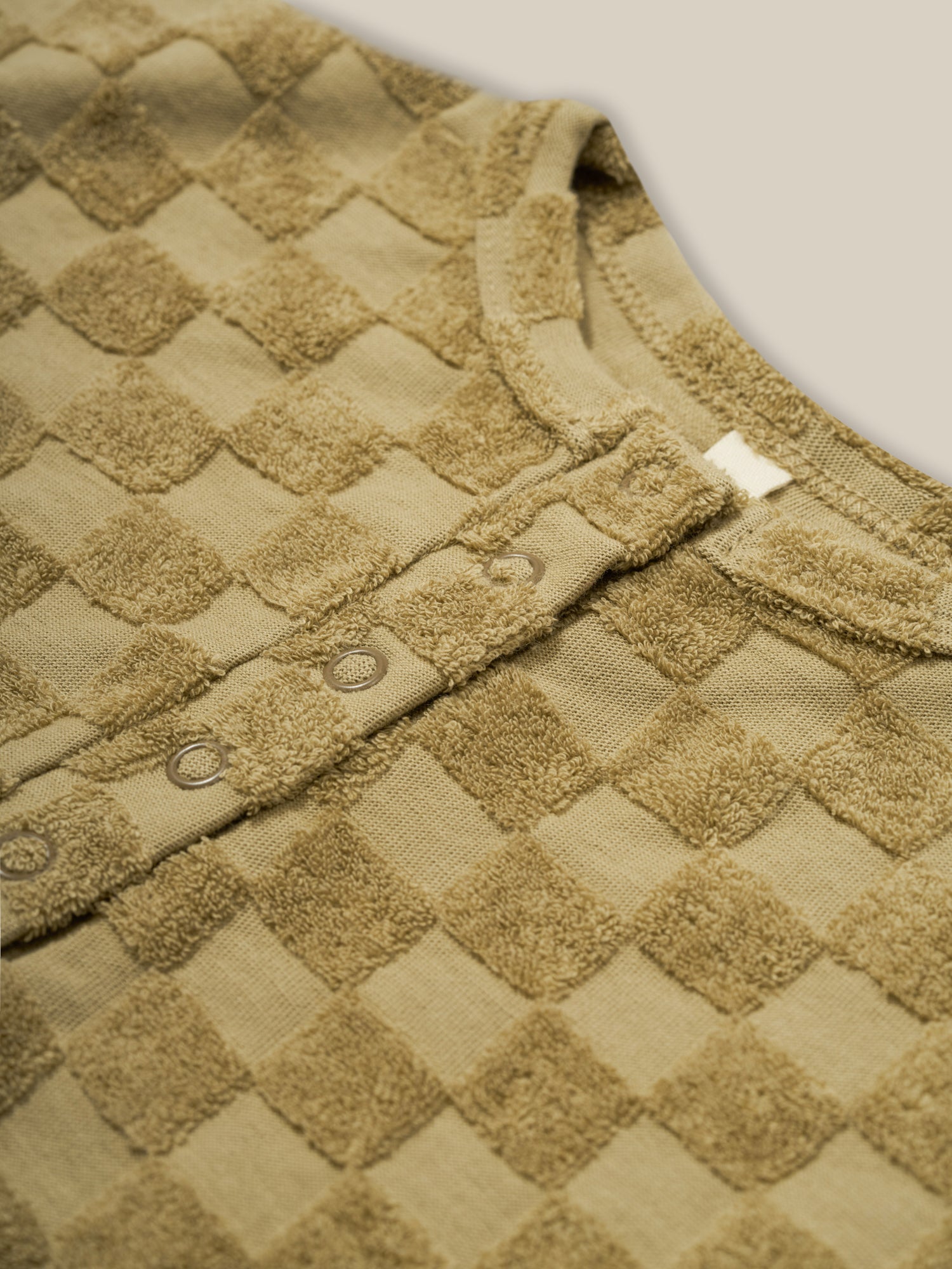 close up of baby & toddler beige checkerboard romper in terry cotton with front & crotch poppers