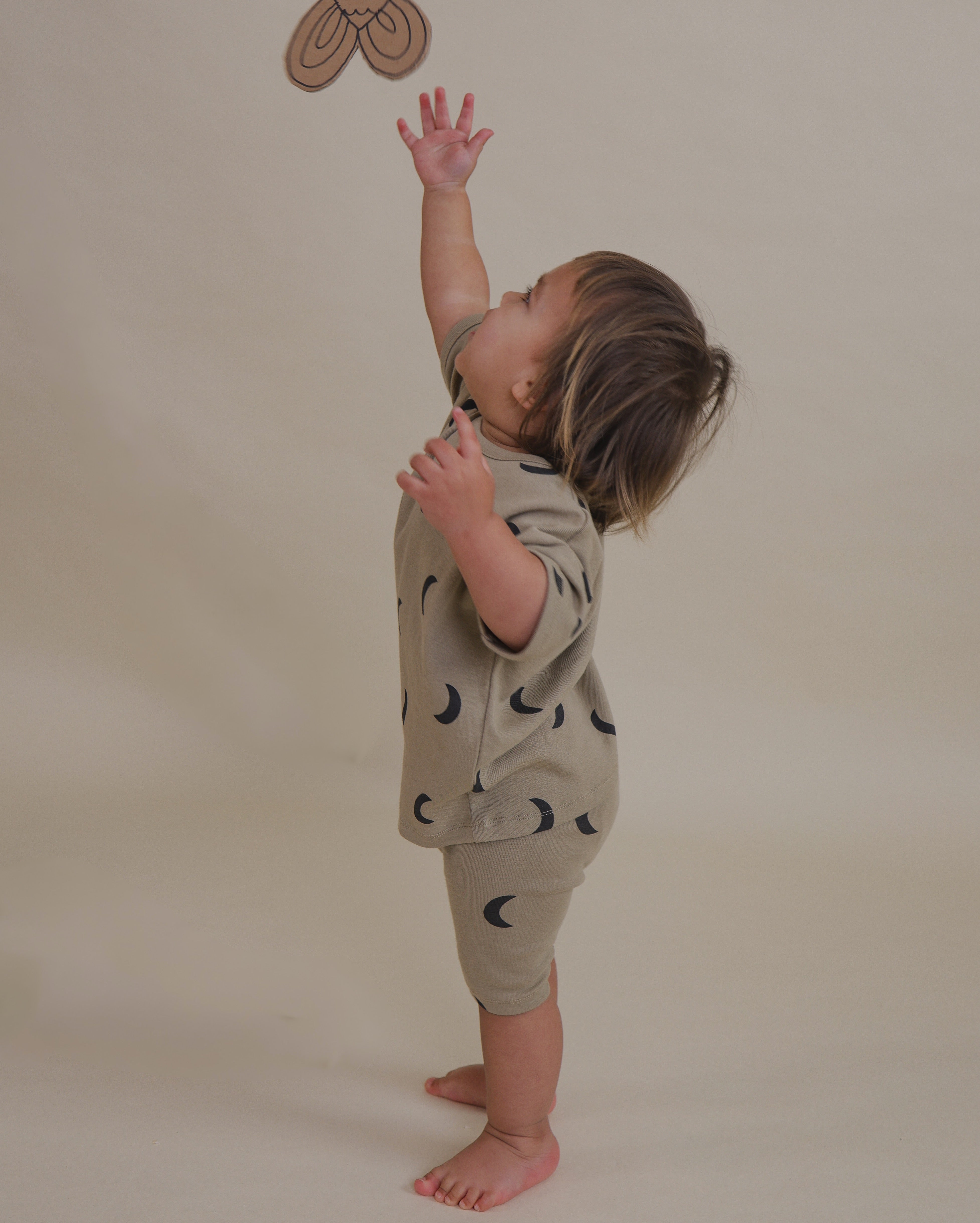 toddler wearing ribbed cotton dusky beige biker shorts with matching shirt reaching for something
