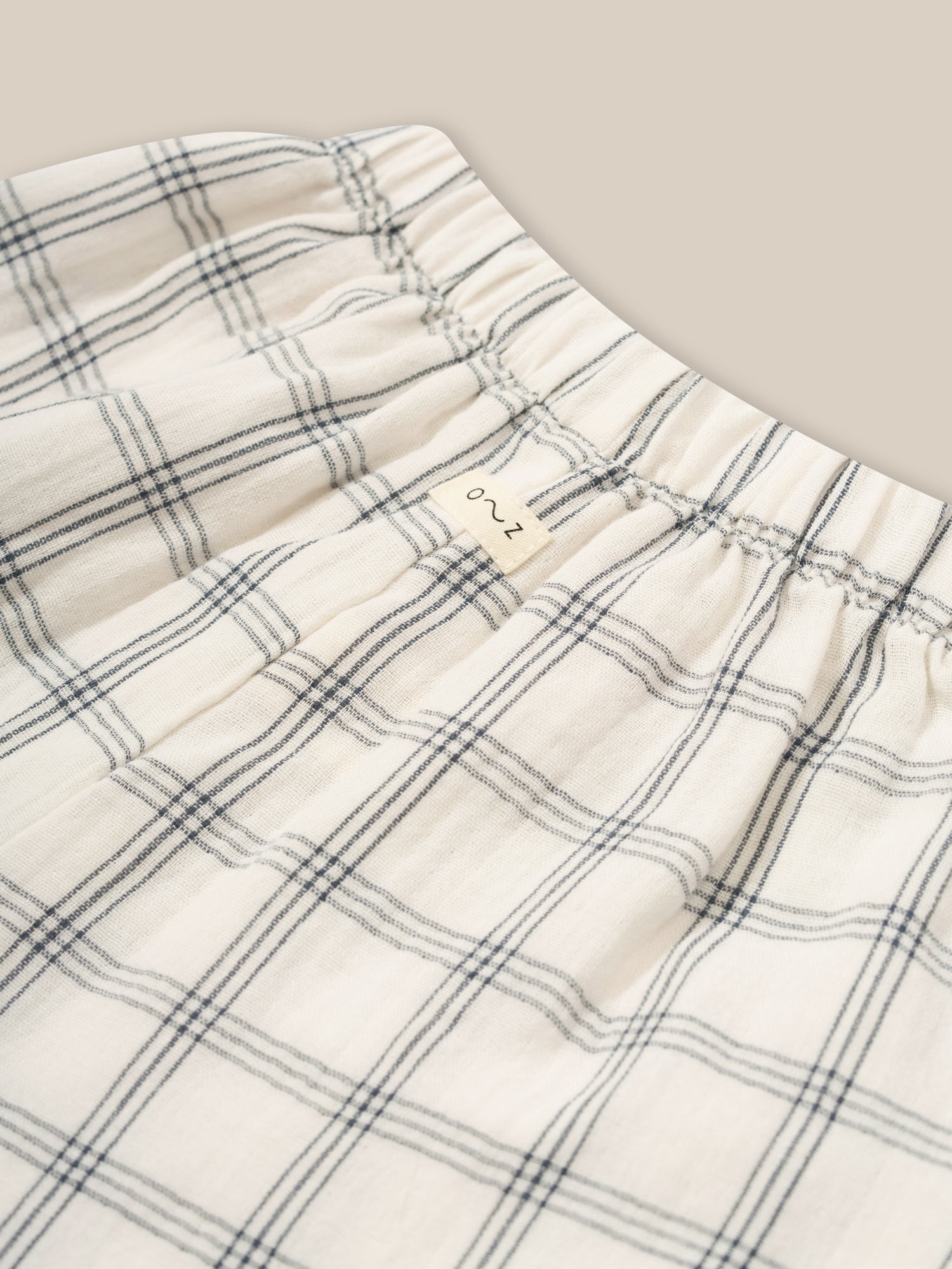 close up of toddler wide leg muslin trousers in white with window check print & elastic waistband