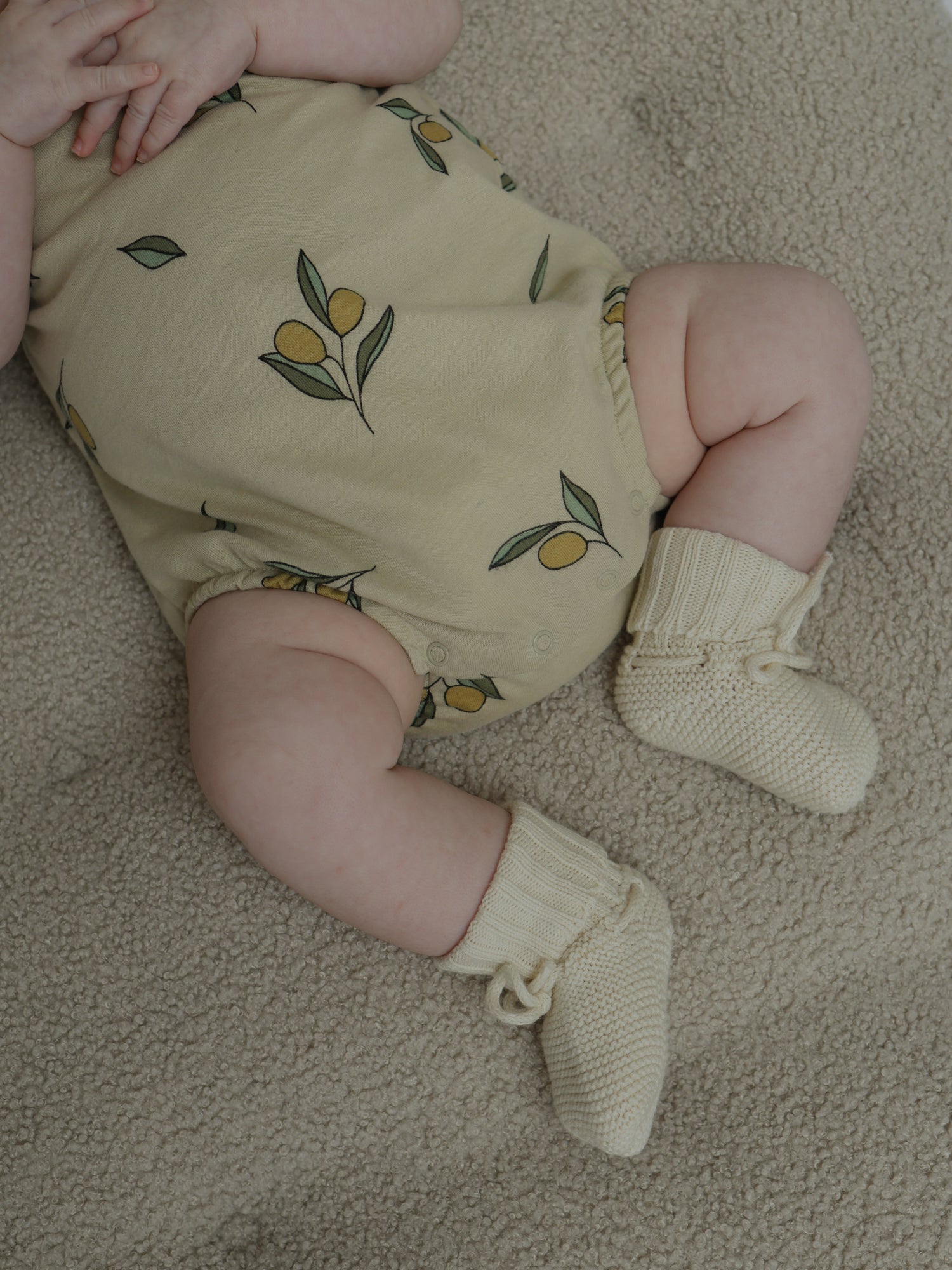 baby wearing cream sleeveless bodysuit with olives & gathered leg opening, booties