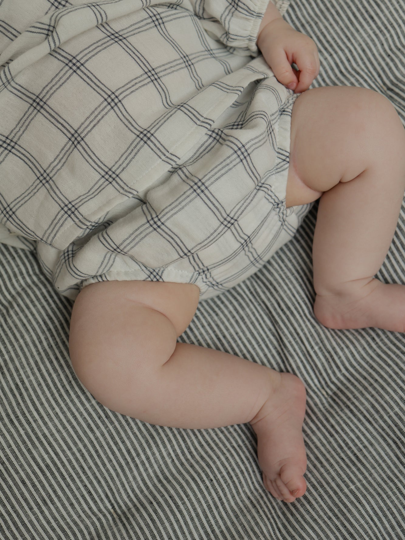 baby wearing white muslin shortie bloomers with navy window check pattern