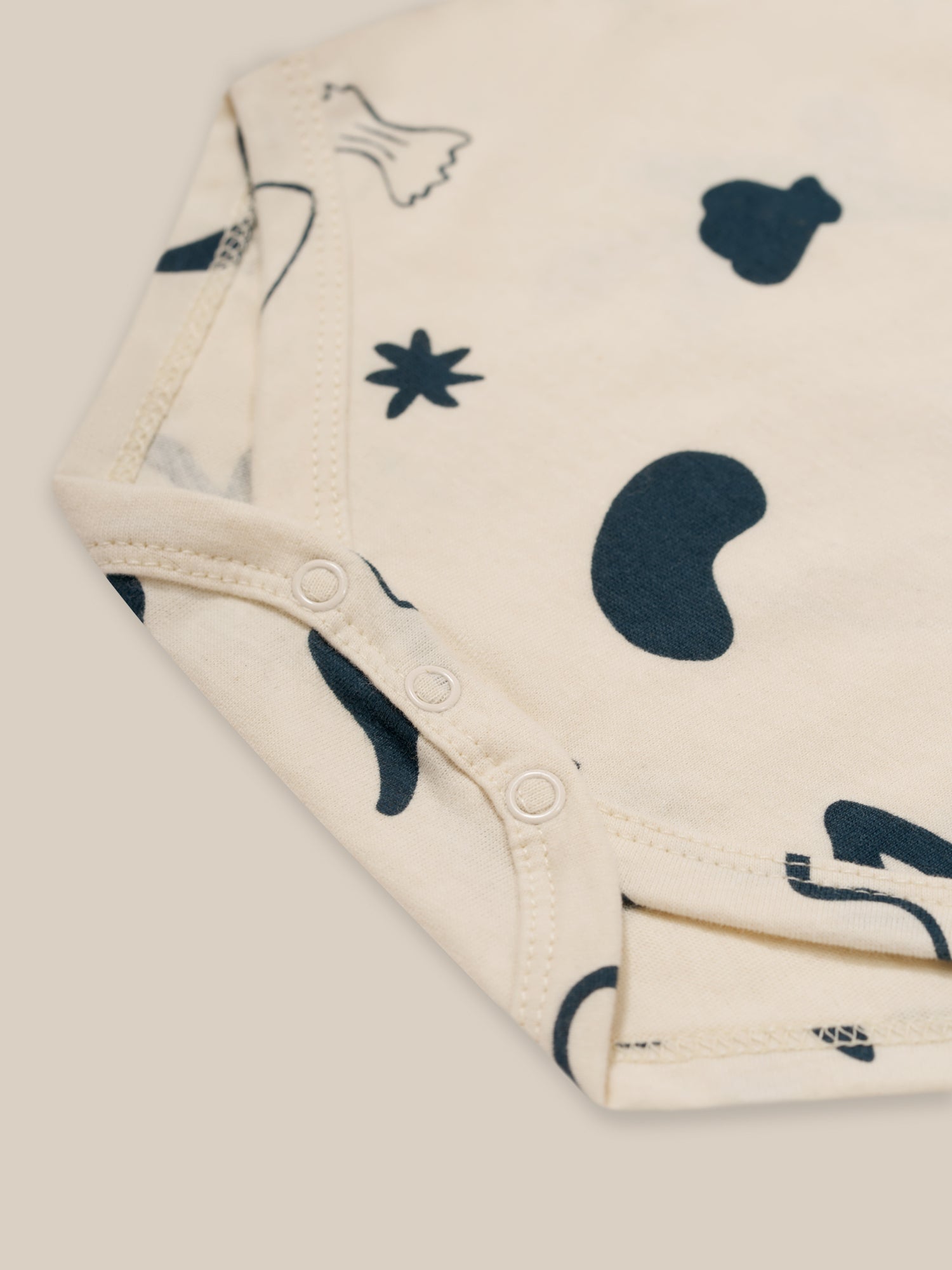 close up of baby undyed cotton short sleeved capri bodysuit with ocean print, shoulder & crotch poppers