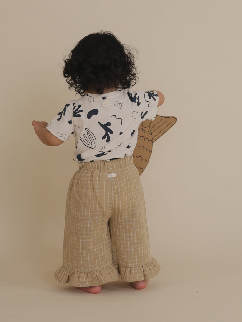 back view of toddler in white crew neck t-shirt with ocean print tucked in trousers, holding cardboard fish