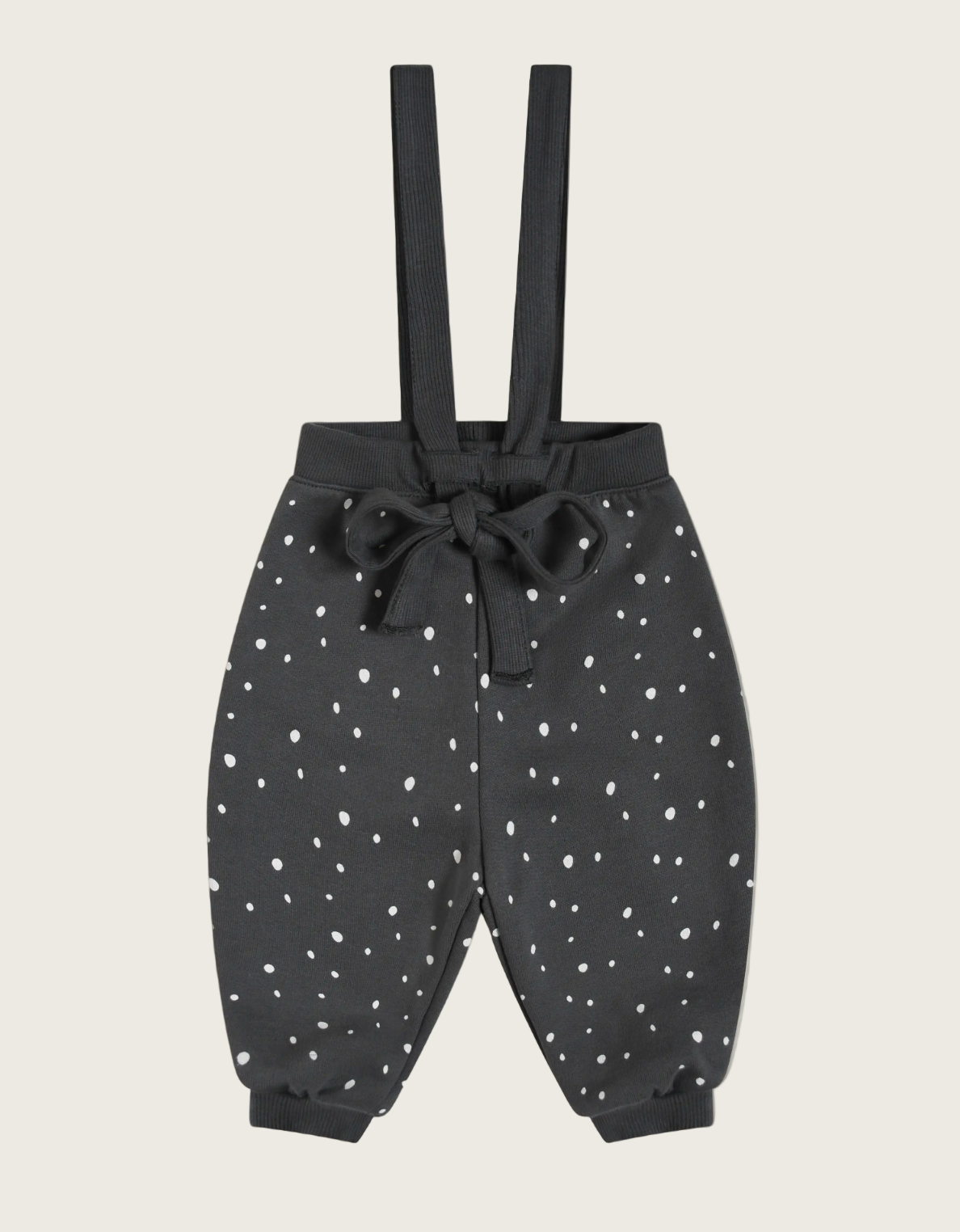 Black pants with white polka dots and suspenders on a beige background