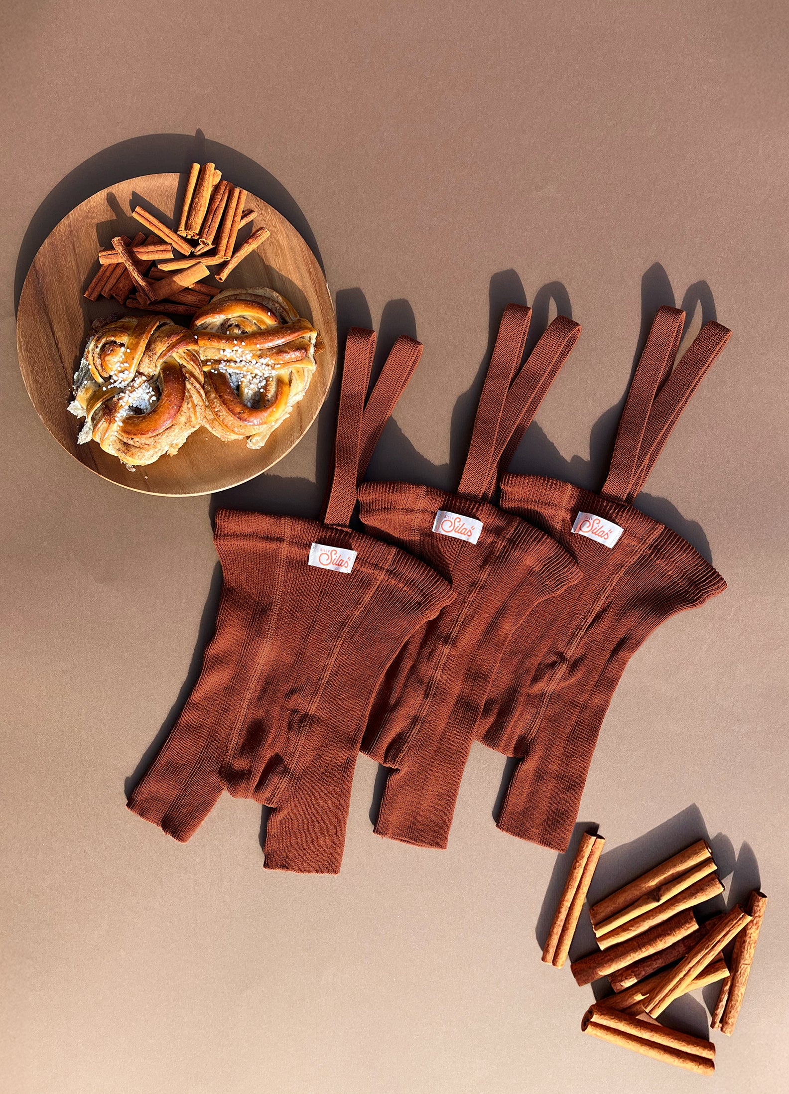 flat lay of baby and toddler cinnamon ribbed shorty tights with braces with cinnamon sticks and buns