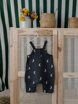 baby & toddler salopette in black with cream moons & poppers hanging on rattan wardrobe door