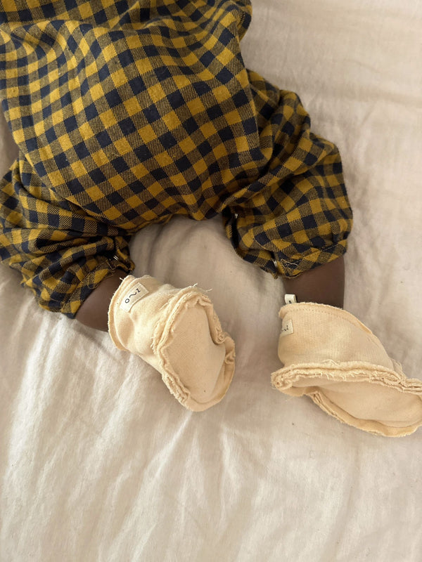 baby in terry cotton cream pebble booties with gingham flannel onesie crawling on bed