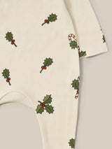 close up of christmas holly & candy cane footed sleepsuit in cream with through front poppers