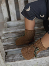 baby in brown wool baby booties with dark green ribbons