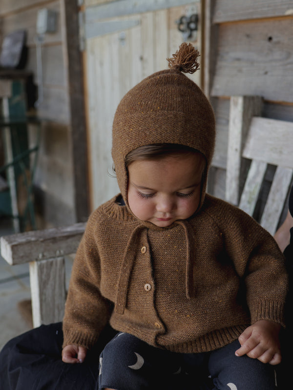 baby wearing brown cardigan with wool tassel hat & black leggings with moon print