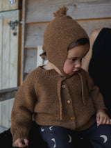 baby in chestnut brown wool cardigan & wool hat with tassel & black leggings