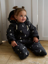 baby in padded winter snowsuit with double zip front white moon print & hood sitting on floor