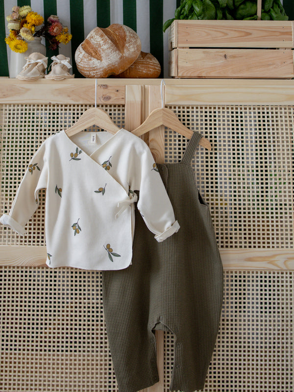 baby & toddler cotton waffle salopette in green & cream kimono with olive print hanging on rattan furniture