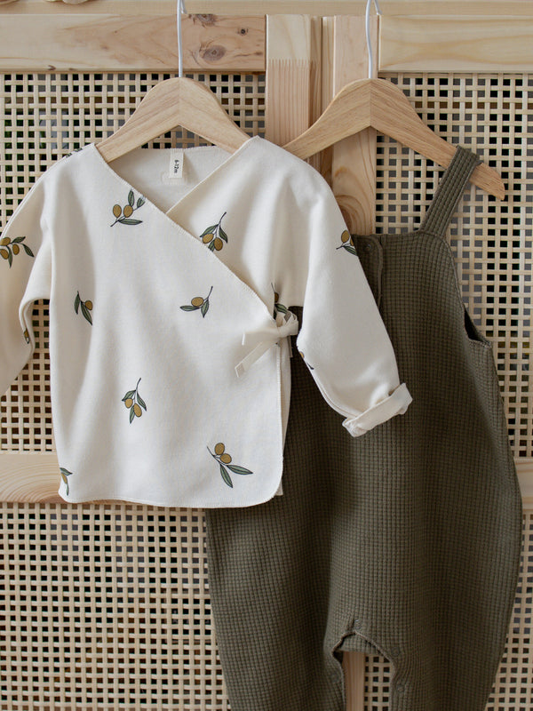 close up of cream kimono with olive print & waffle salopette hanging on rattan cupboard