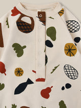 close up of cream long-sleeve onesie with fruits vegetables & basket prints front & crotch poppers