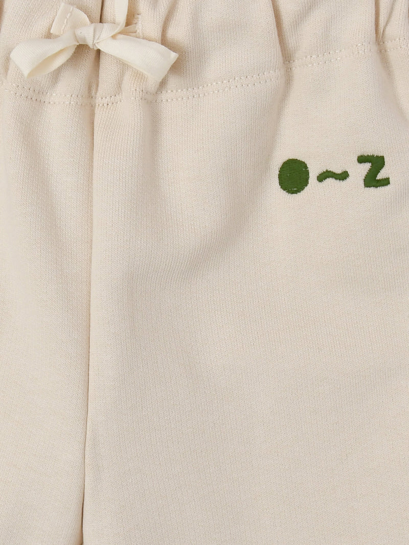 close up of undyed cotton drawstring sweatpants in cream with O ~ Z embroidered in green