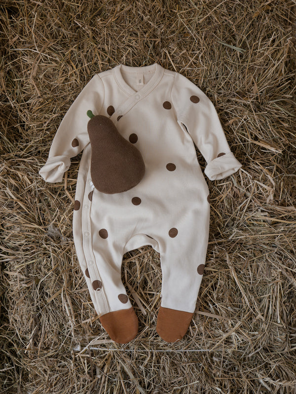 baby undyed cotton cream footed suit with gold dots brown feet & pear rattle toy on farm straw