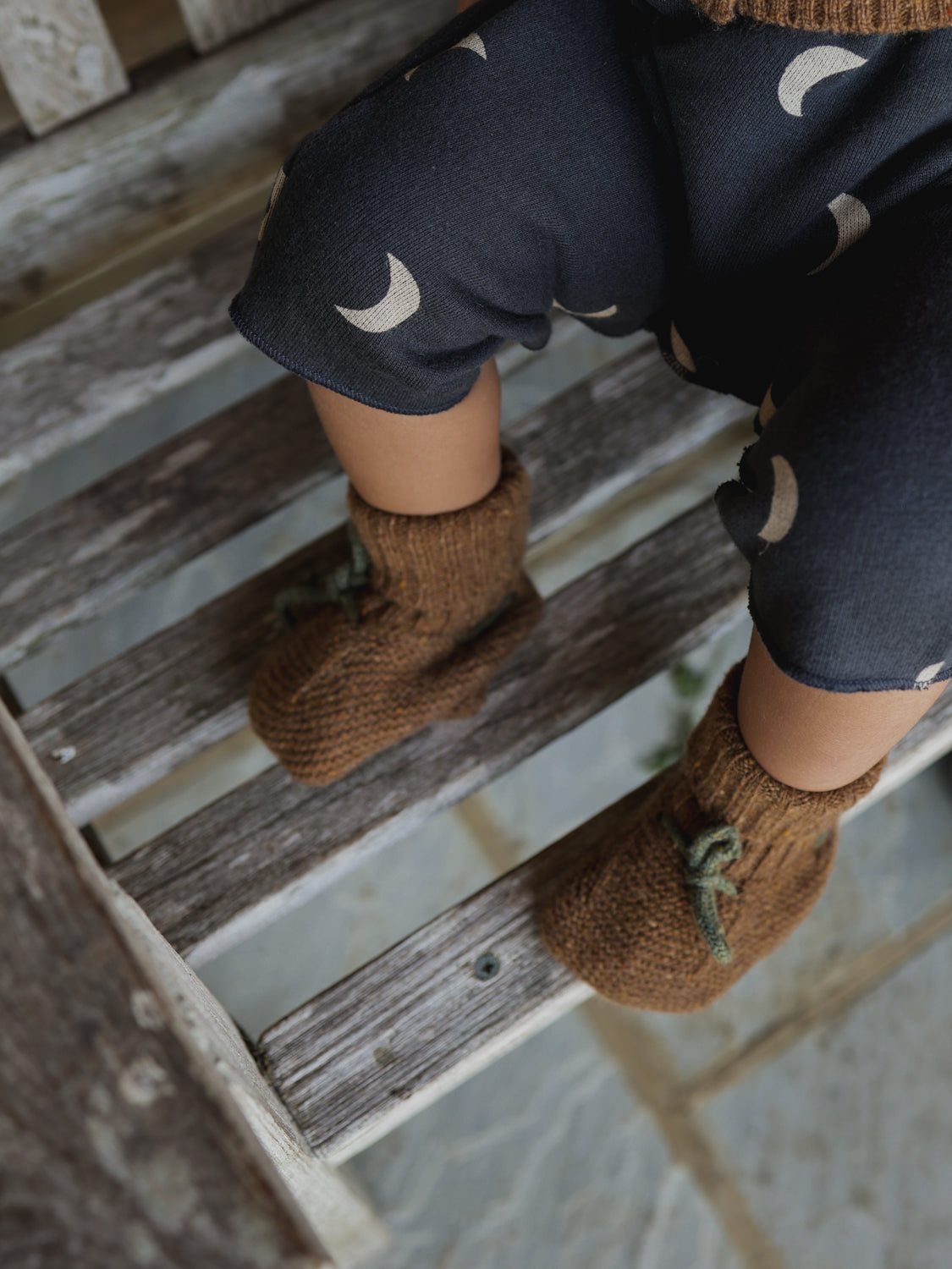 baby wearing leggings & wool baby booties in chestnut brown with dark green ribbons