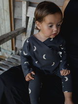 baby wearing charcoal black cotton kimono with cream moons & matching leggings sitting on mum's lap