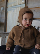 baby wearing chestnut brown wool cardigan with matching wool hat & black leggings with moon print