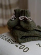 baby forest moss green wool booties stacked on folded wool cardigan & ORGANIC ZOO bag