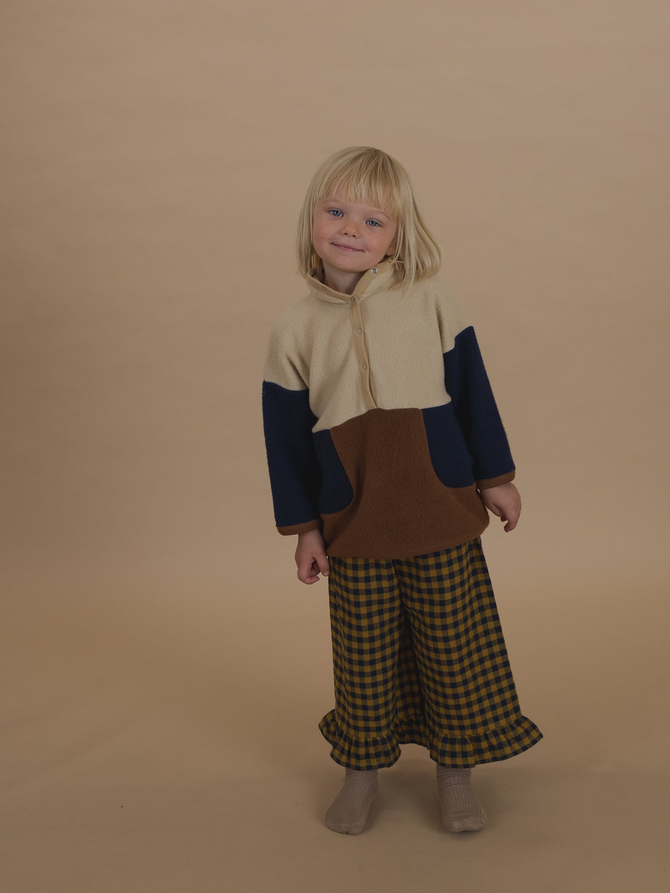 toddler in navy and yellow gingham culottes with frill hems, and colour block sweater with high collar
