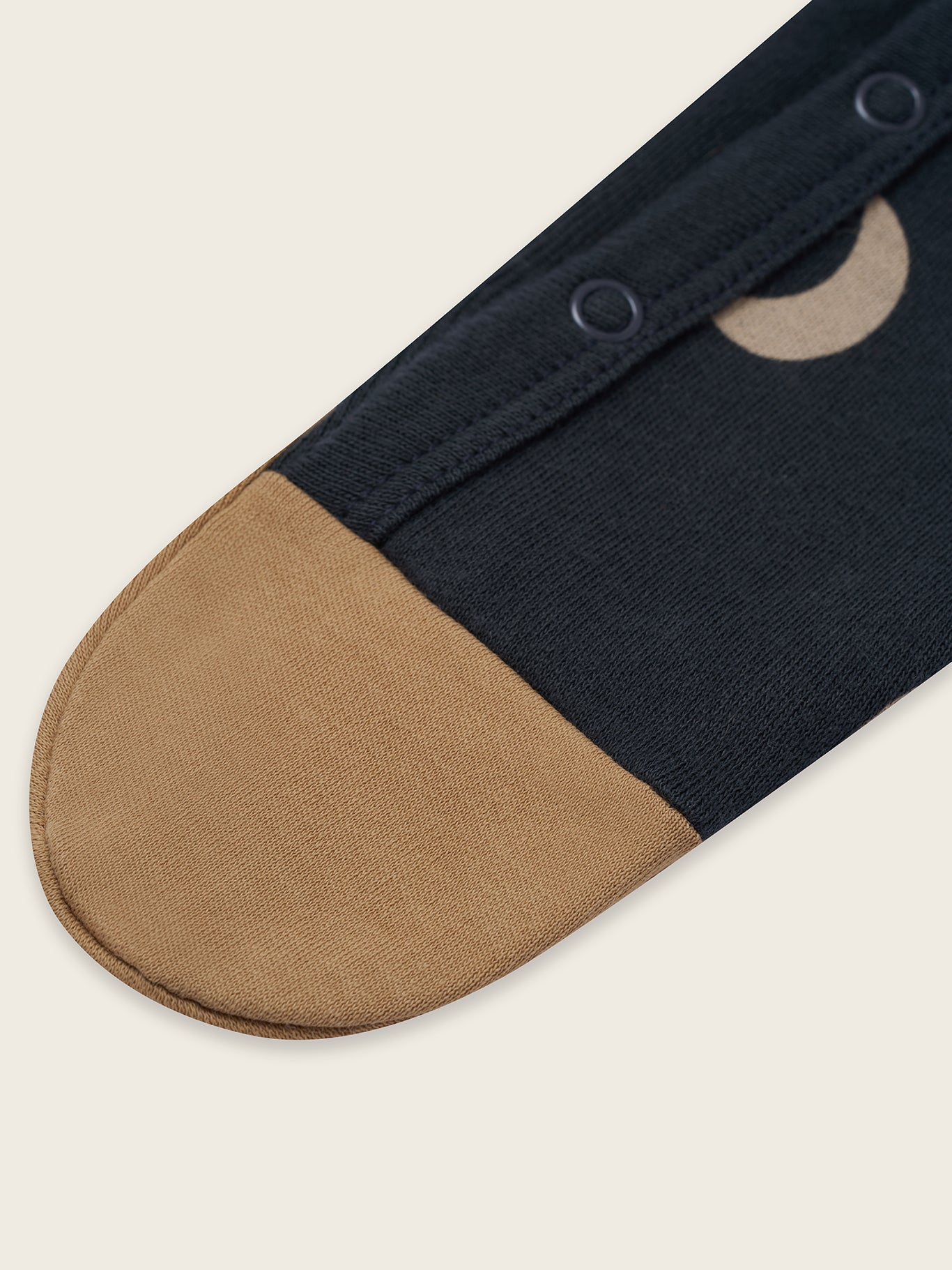 Navy and beige onesie detail on a light beige background