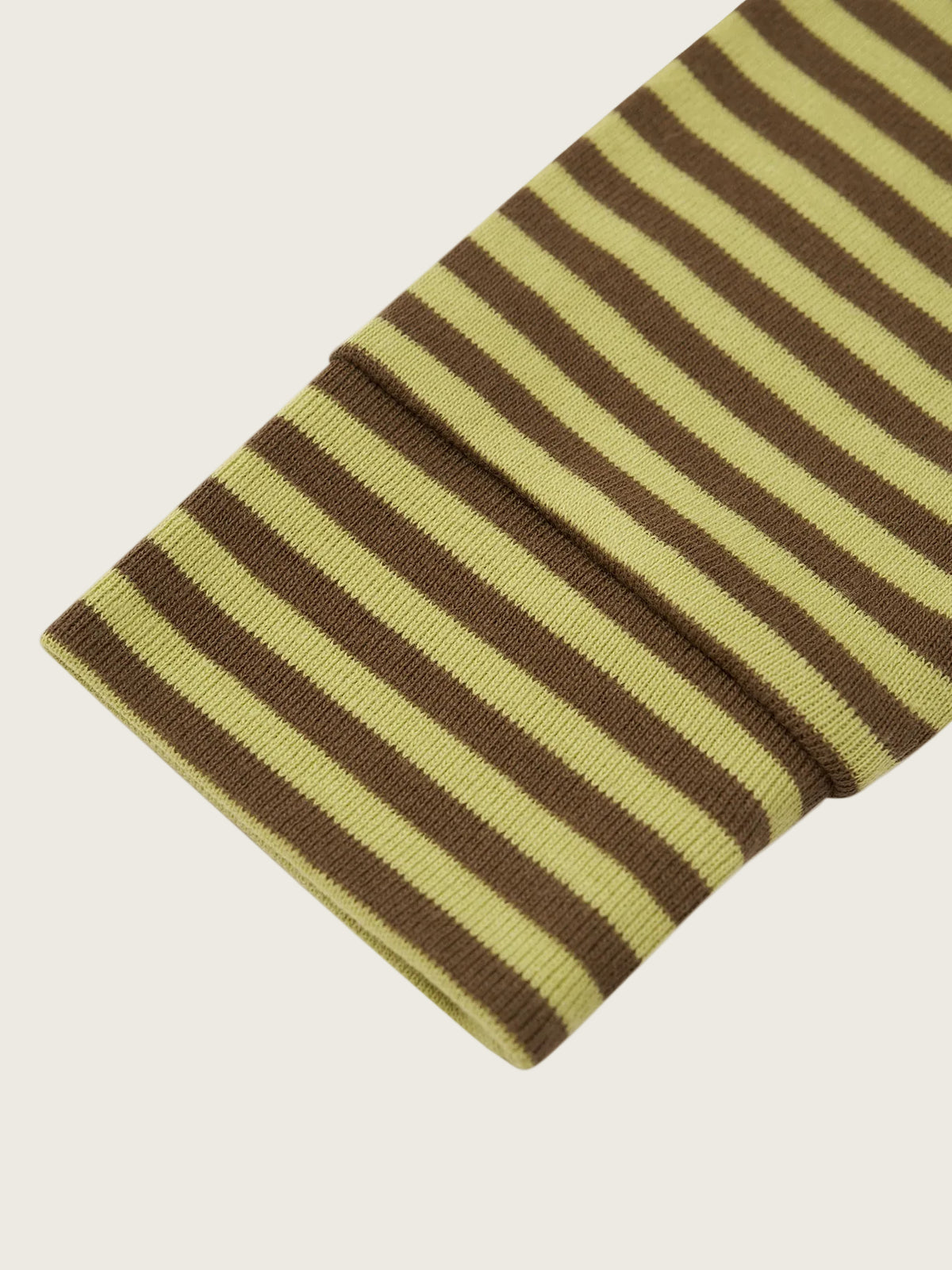 A close-up of a ribbed knit fabric with alternating olive green and dark brown horizontal stripes, folded over on a light beige background.