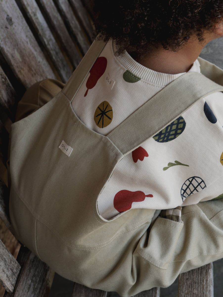 close up of toddler clothes oversized cotton dungarees & sweatshirt with fruits & plants illustrations