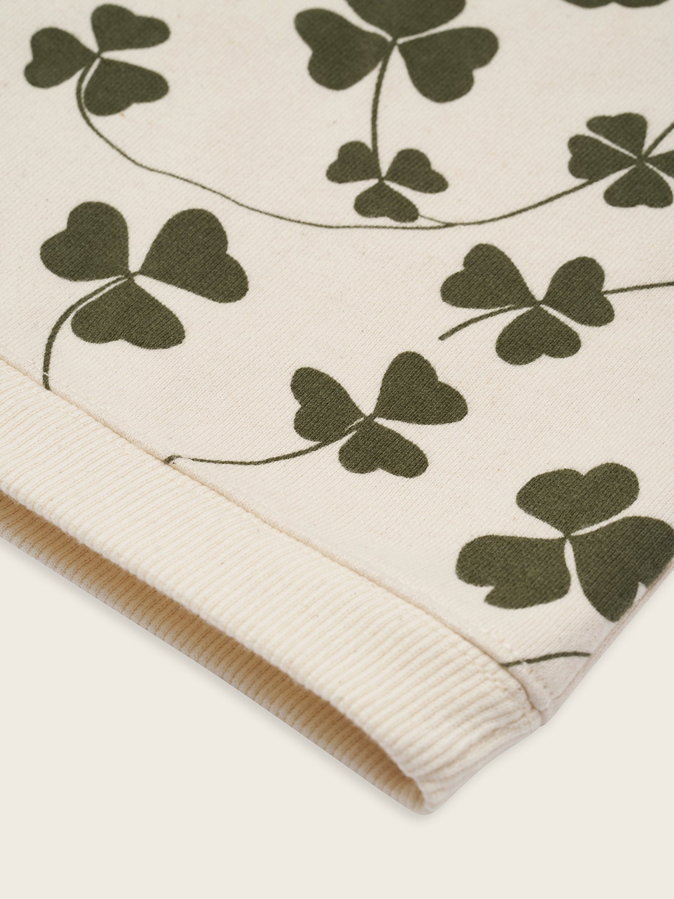 close up of baby and toddler cream undyed cotton sweatshirt with green clover print