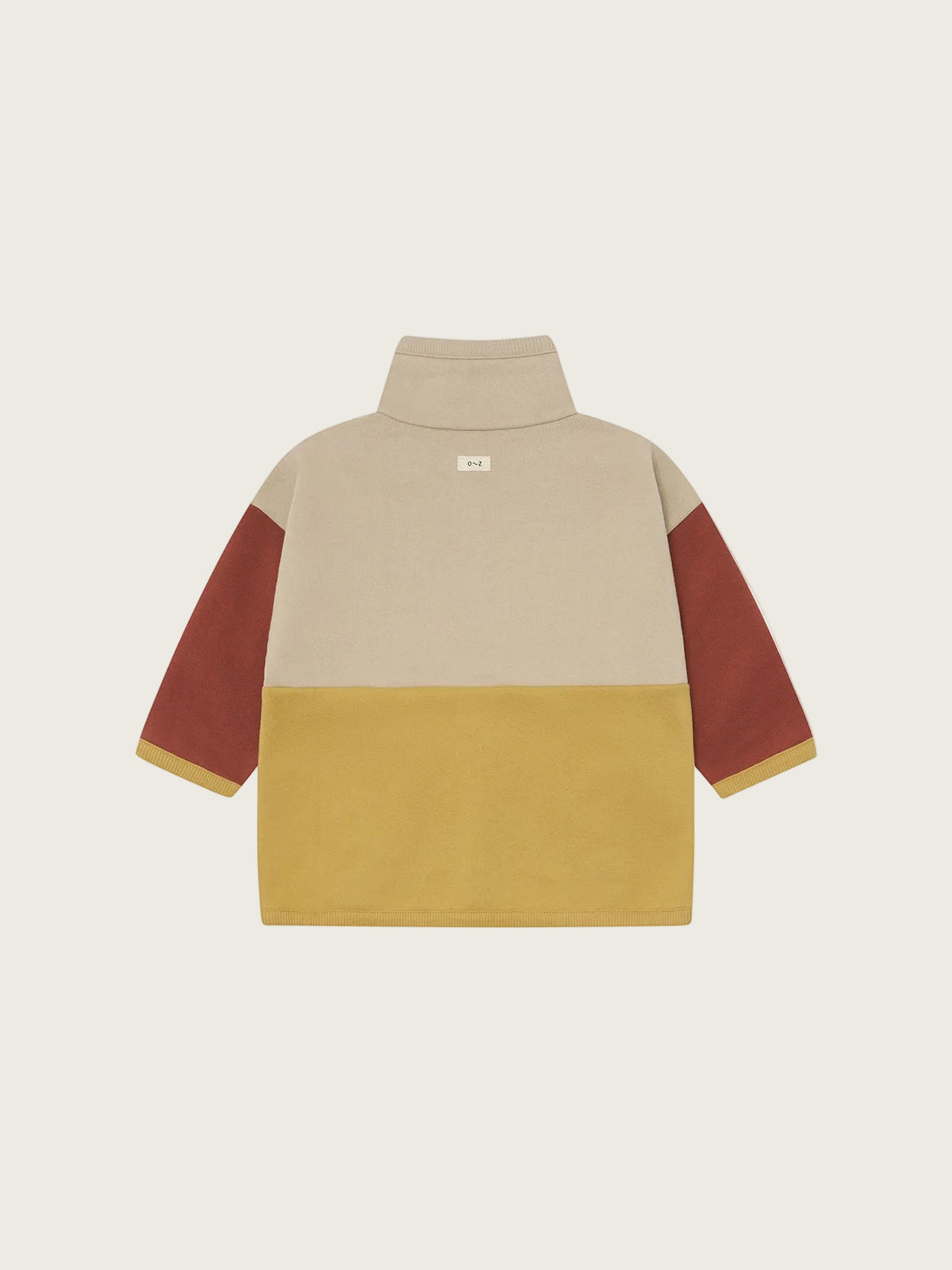 A color-blocked long-sleeve mock neck top shown from the back, featuring a beige upper back, a mustard yellow lower back, and rust brown sleeves with thin yellow piping.