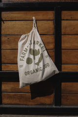 cream cotton storage bag with green FARMERS MARKET ORGANIC ZOO logo & text hooked on wooden slats