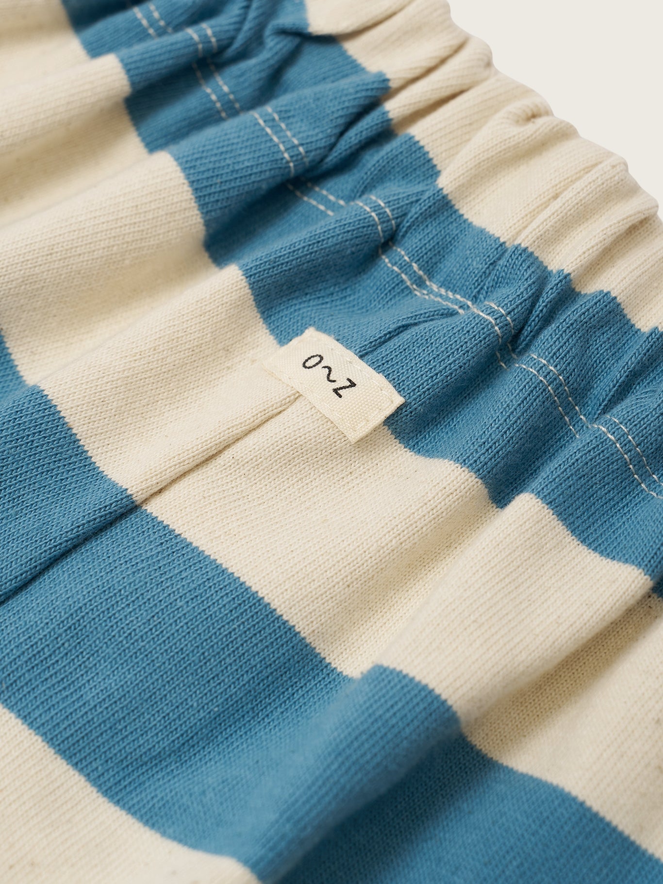 Close-up of blue and beige striped fabric with a size label.