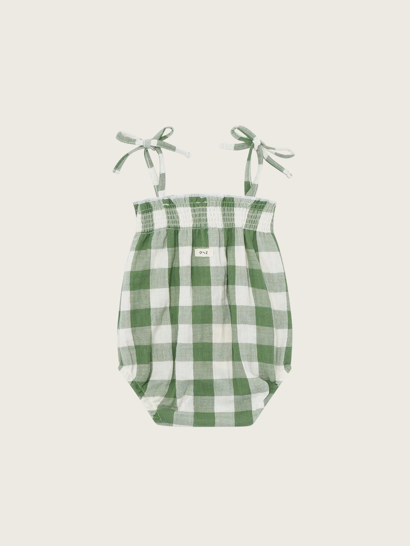Green and white checkered baby bodysuit with straps on a white background