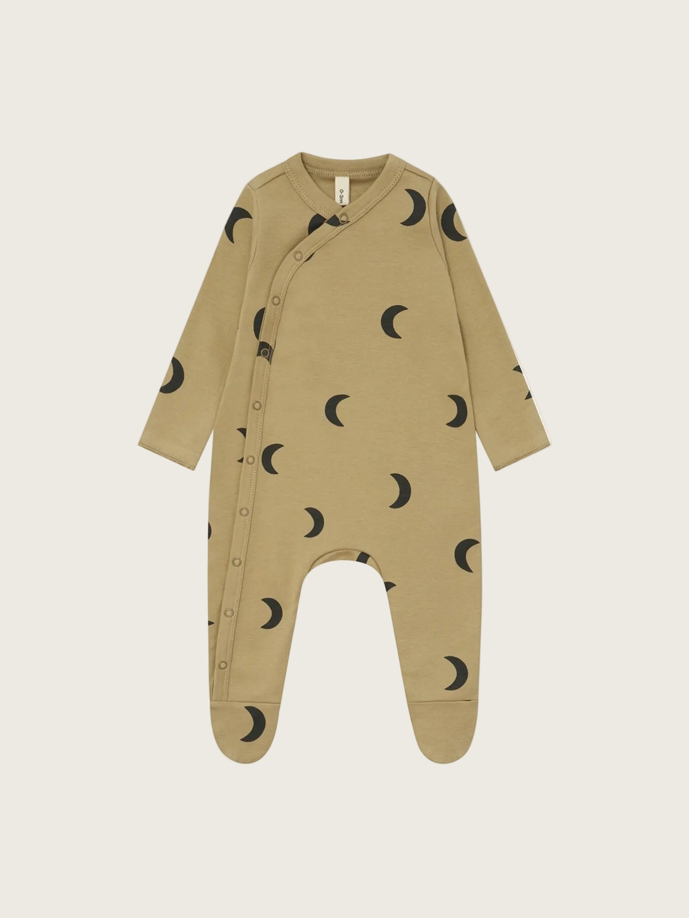 A baby long-sleeve footed sleeper in a warm tan color, featuring a black crescent moon pattern all over and snap buttons down the front, shown on a plain white background.