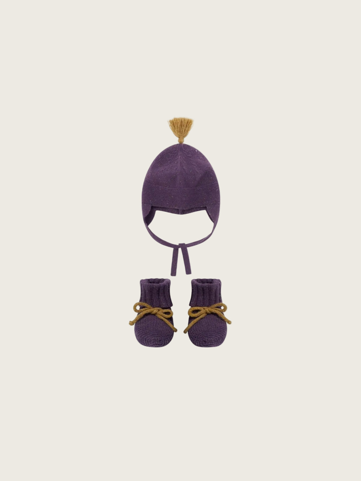 A baby knit hat and bootie set in deep purple, featuring a small mustard yellow tassel on the hat and matching mustard yellow bow details on the booties, shown against a plain white background.