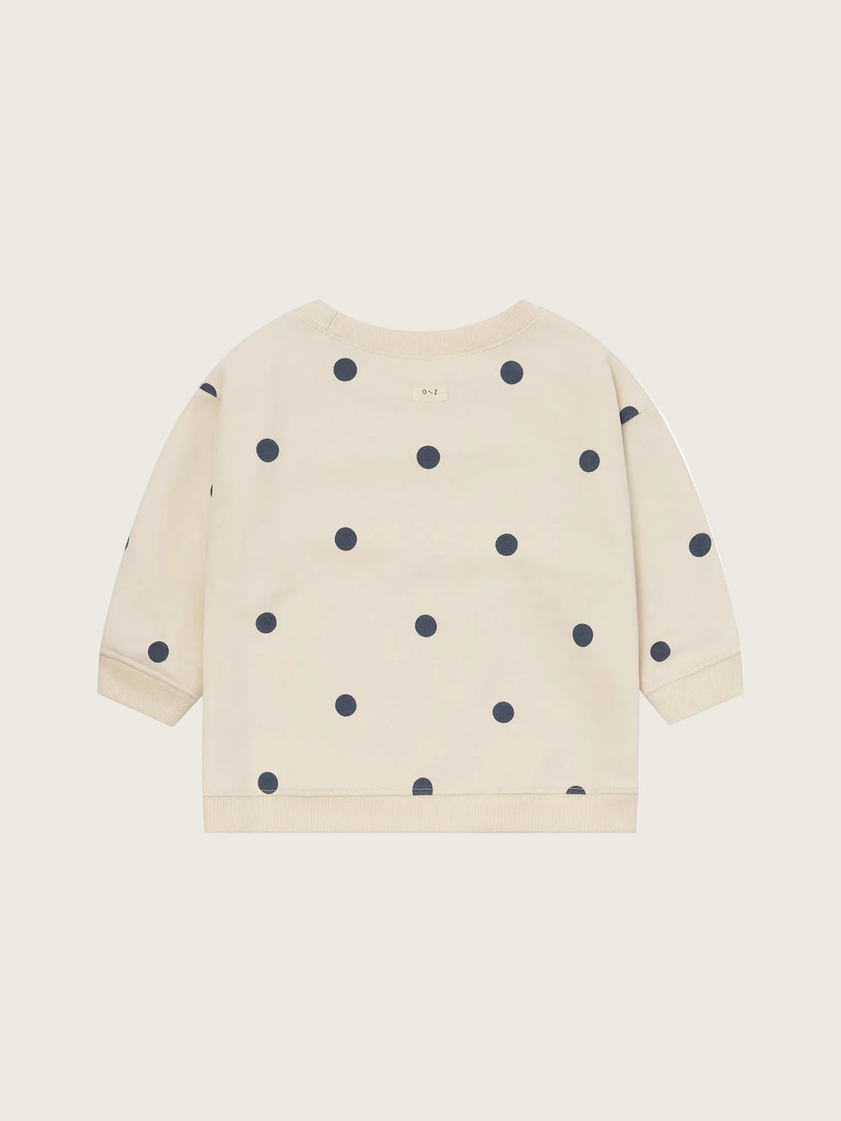 A cream-colored long-sleeve sweatshirt with dark navy blue polka dots, shown flat against a solid white background.