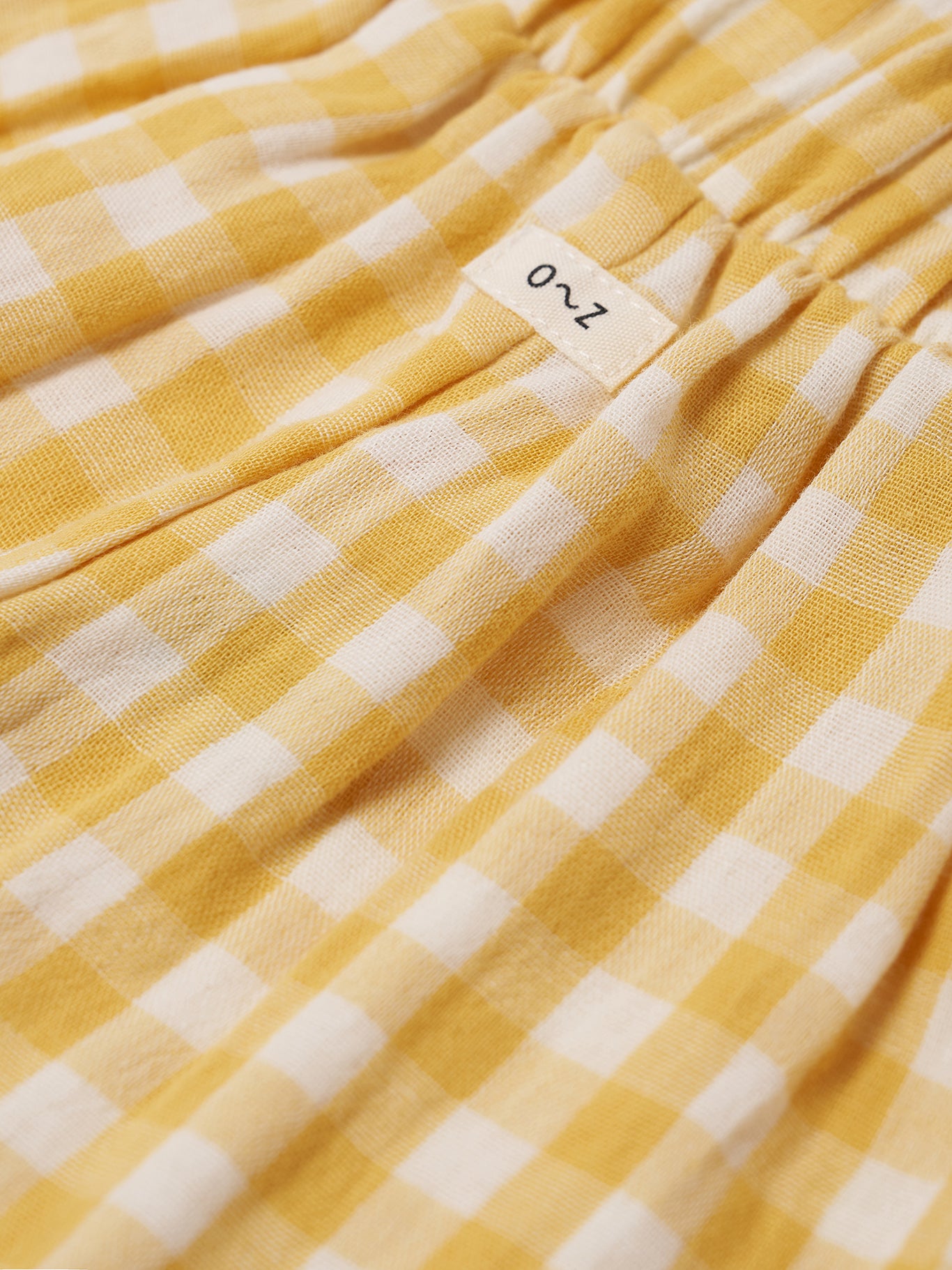 Yellow and white checkered fabric with a brand label on a yellow background
