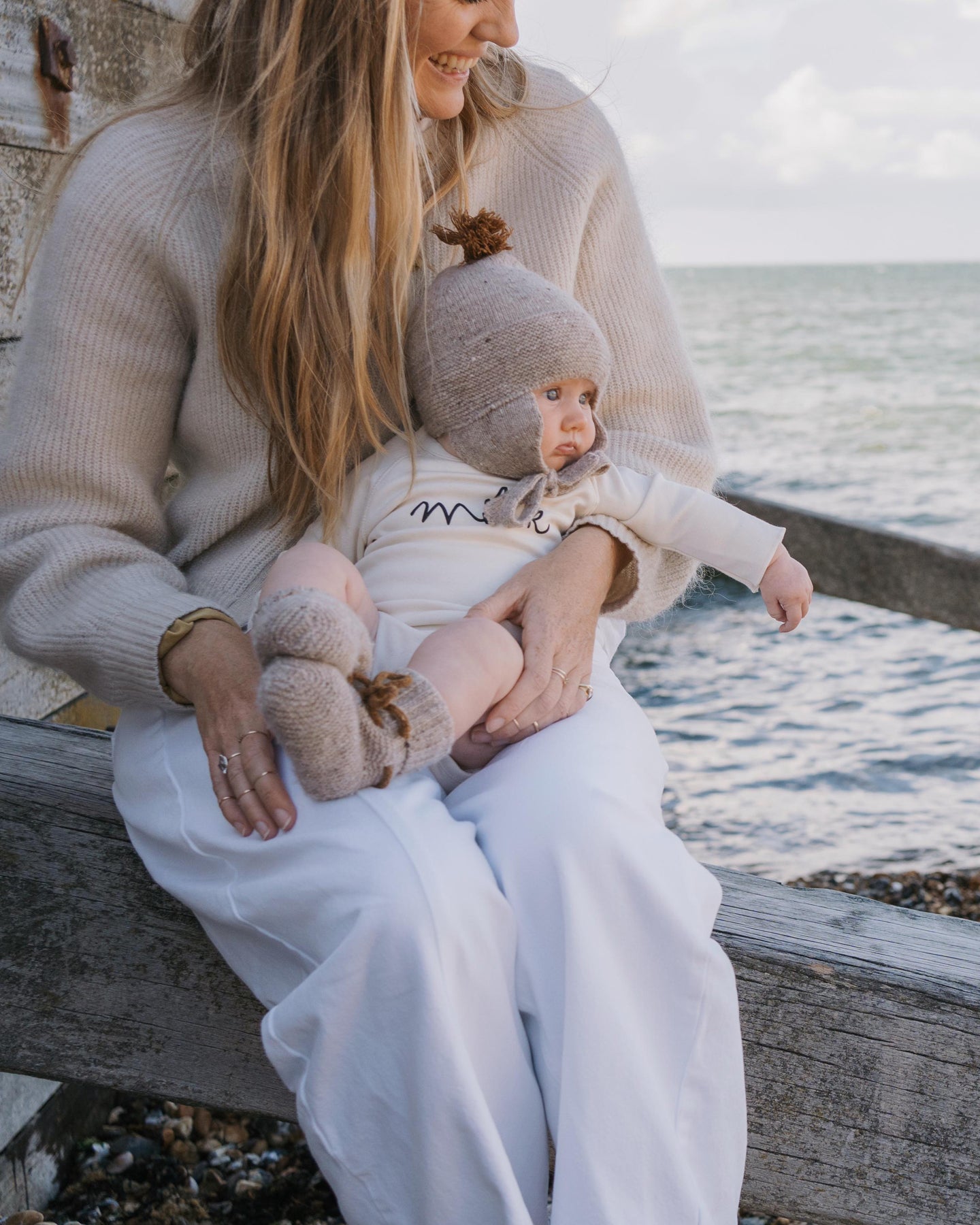 Mom holding a baby in undyed cotton bodysuit by the water