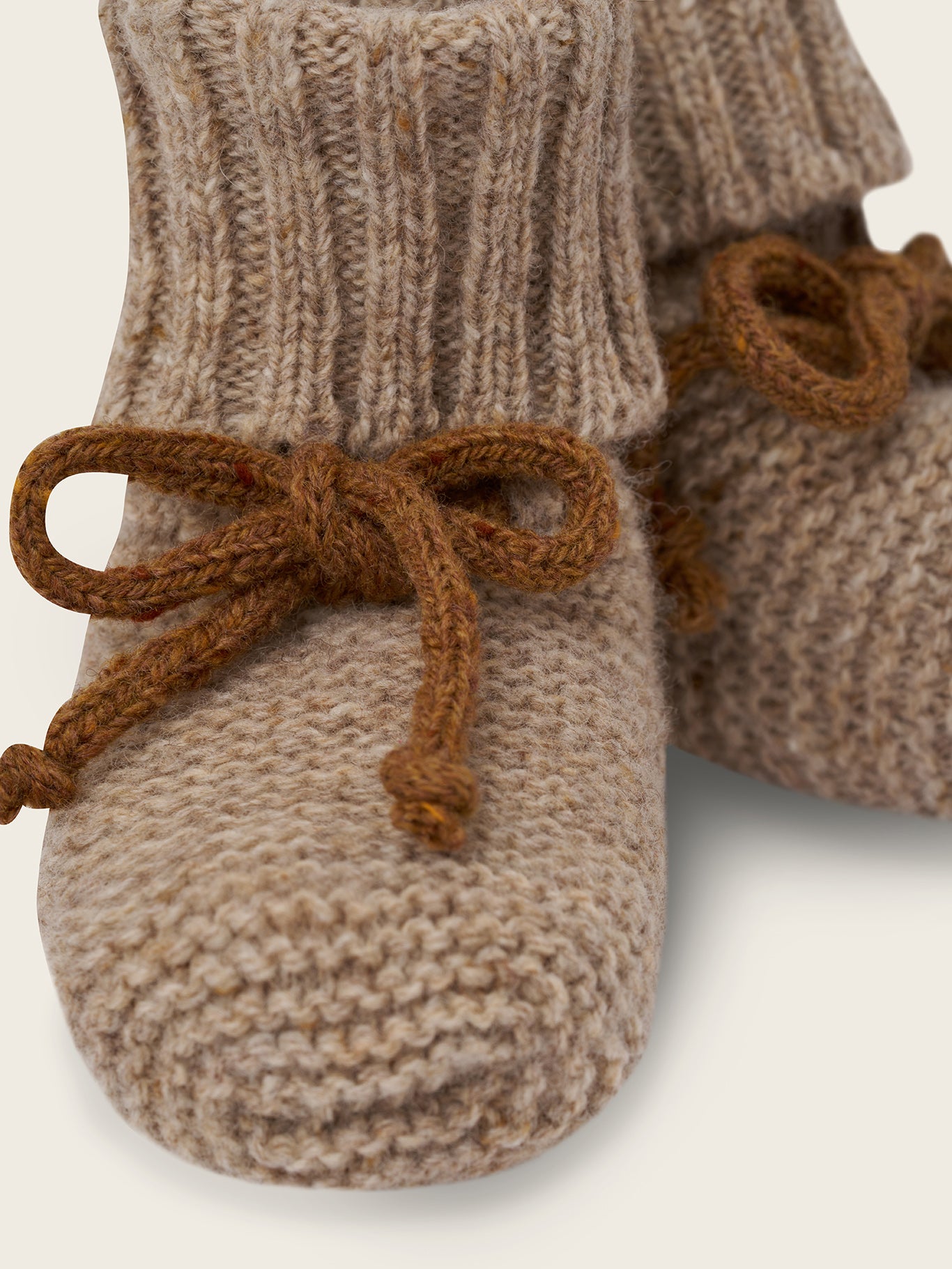 close up of wool booties in oatmeal with ribbed cuffs and brown ribbons