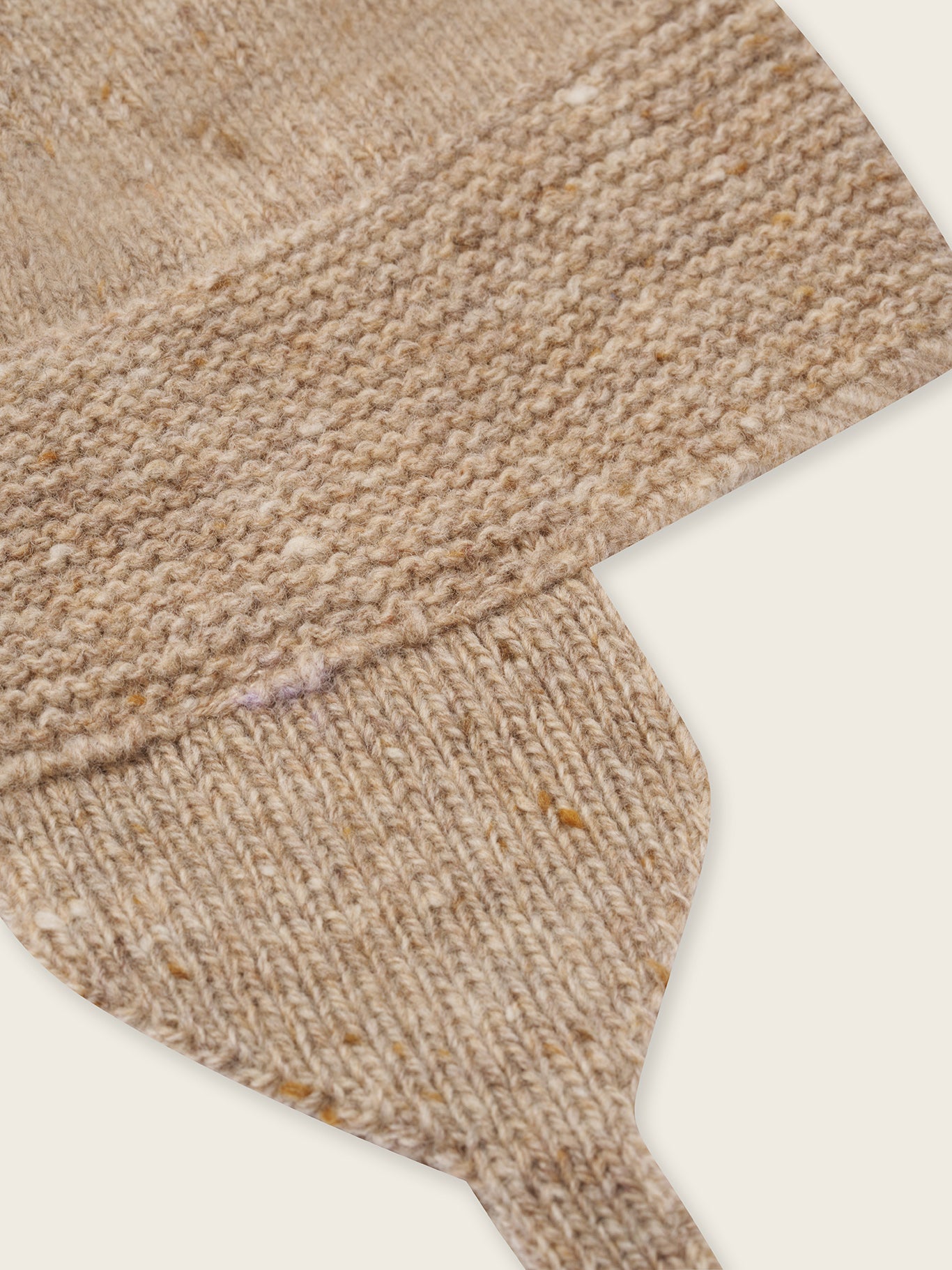 close up of baby wool hat in oatmeal with brown tassel and chin tie
