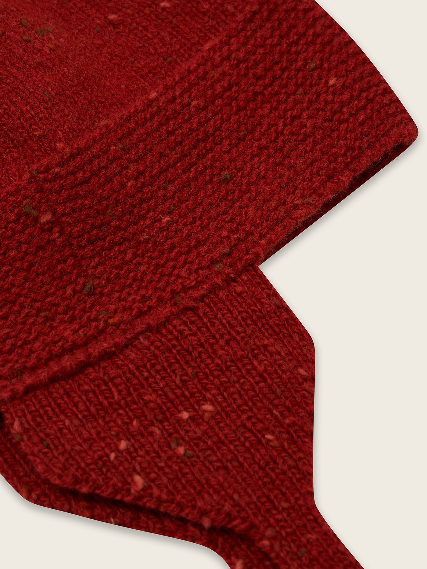 close up of wool hat in paprika red with oatmeal tassel and chin tie