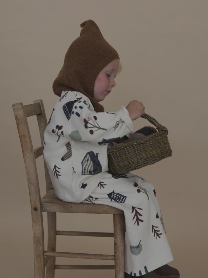 toddler in chestnut brown wool knitted balaclava, matching sweatshirt & pants, putting toy in basket