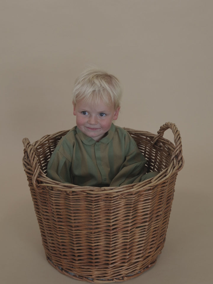 toddler in stripes lodge shirt with balloon sleeves & matching trousers, standing in basket & waving