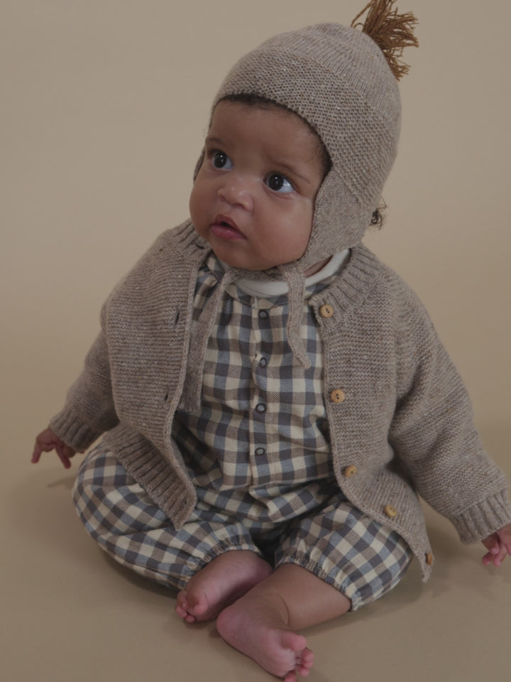 baby in cream and blue gingham flannel onesie, and matching oatmeal wool tassel hat and cardigan